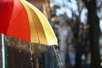 Open bright umbrella under pouring rain outdoors, closeup. Space for text