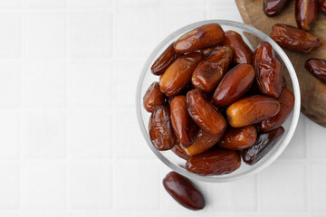 Tasty dried dates in glass bowl on white table, top view. Space for text