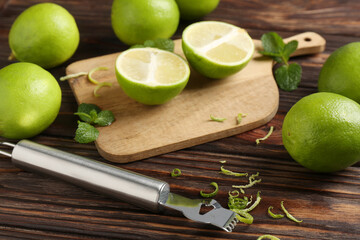 Lime zest, zester, mint leaves and fresh fruits on wooden table, closeup