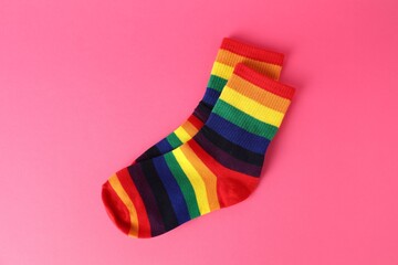 Pair of socks in LGBT colors on pink background, top view