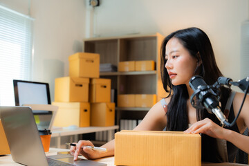 Young entrepreneur woman working at her home office selling online, preparing a package and using a...
