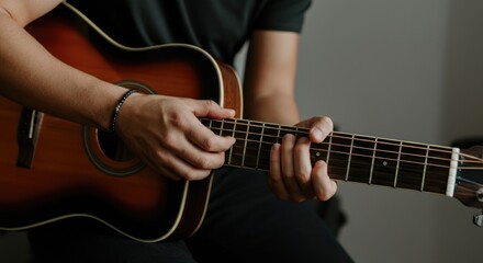 Obraz premium Person playing acoustic guitar, focusing on hands and guitar strings