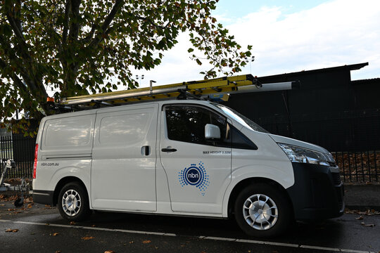 Side view of a parked National Broadband Network van, a white Toyota HiAce, featuring the NBN logo and internet web address