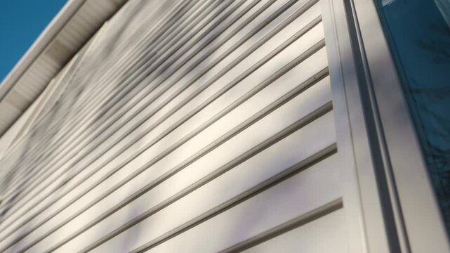 White siding house wall with clean, modern panels, providing a sleek and classic exterior look. Wide move camera view