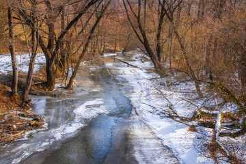 Frozen river covered by snow in the winter forest.