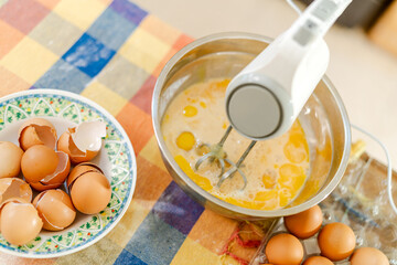 Pastry chef whisking eggs in bowl with electric mixer