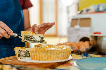 Chef serving slice of freshly baked chard tart in kitchen