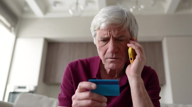 Trusting serious feared pensioner giving away card number to fraudsters over phone. Financial scam, identity theft, bank card fraud, information theft manipulation, deception, vulnerable individual