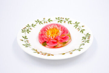 colored flowers in jelly on a white plate on a white background. Pudding with colored flowers. Jelly cake in the shape of a flower. The gentle sweetness. Gentle tone. Close up
