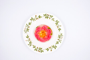 colored flowers in jelly on a white plate on a white background. Pudding with colored flowers. Jelly cake in the shape of a flower. The gentle sweetness. Gentle tone. Close up