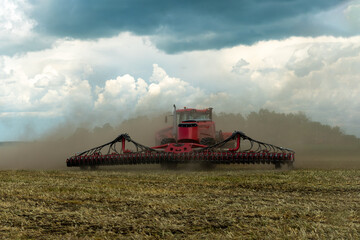 Red tractor working in field on a bright sunny day. The concept of work in a fields and agriculture...