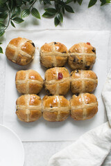 Overhead view of hot cross buns on white parchment paper, top view of hot cross buns on a white background, process of making hot cross buns