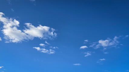 Bright and serene blue sky scattered with fluffy white clouds, depicting the beauty of tranquility. Perfect background for concepts such as freedom, nature, and vastness.