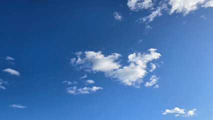 Bright and serene blue sky scattered with fluffy white clouds, depicting the beauty of tranquility. Perfect background for concepts such as freedom, nature, and vastness.
