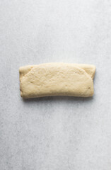 Overhead view of steamed bun dough being folded, top view of mantou dough being rolled out, process of making steamed milk buns