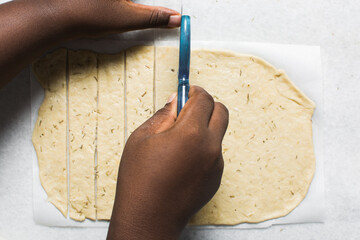 Overhead view of crackers dough on parchment paper being sliced, cutting cracker biscuit dough on...