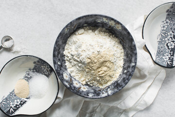 overhead view of mise en place for making homemade bagels, ingredients for making bagels on a marble countertop