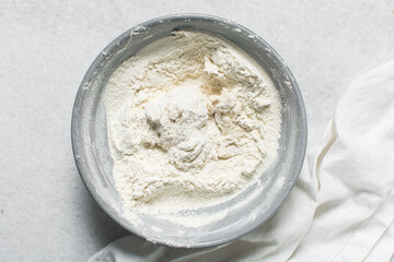 Overhead view of bagel dough being mixed in grey bowl, top view of homemade bagel dough being mixed in bowl, process of making bagels