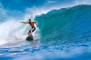 Male surfer on a blue wave at sunny day