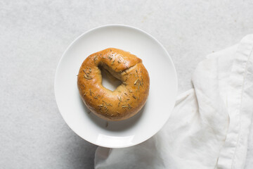 Overhead view of freshly baked bagels on white serving tray, top view of homemade bagels on white plate, process of making bagels