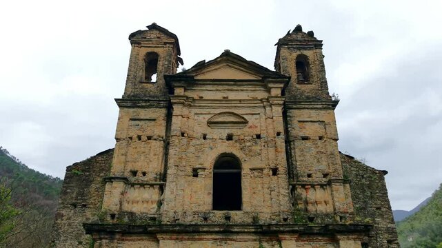 Crumbling facade of Chiesa San Michele Arcangelo, a testament to time and decay, set against a serene valley backdrop