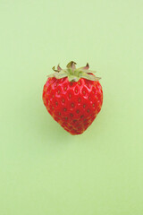 a single red strawberry on a green background