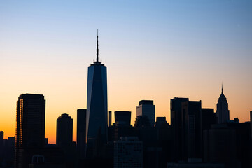 City skyline at dusk stock-image with a golden sunset glow illuminating towering skyscrapers, casting vibrant reflections on glass windows, under 