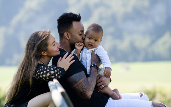 Multiethnic parents Biracial baby in park. Multiracial couple outdoor portrait. Biracial baby child with parents in backyard. Diverse family. African american father mother with baby, family portrait. - Powered by Adobe