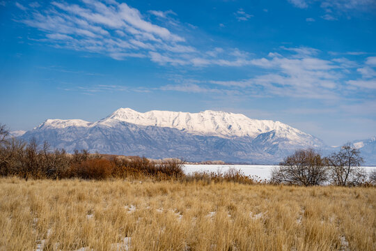 utah lake from Saratoga Springs snow-capped mountain range with dry grass and a frozen lake