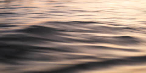 Abstract photograph of the ocean's surface taken from a moving boat. The motion blur creates a dreamy, ethereal effect, with the water's texture and subtle color variations highlighted.