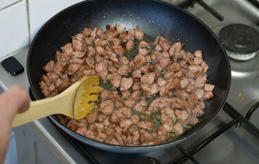 frying finely chopped sausage in a pan on gas. frying sausage in oil.
