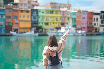 woman traveler visiting in Taiwan, female Tourist with backpack sightseeing at Keelung, Colorful Zhengbin Fishing Port. Popular landmarks and attractions near Taipei City.  Asia Travel concept