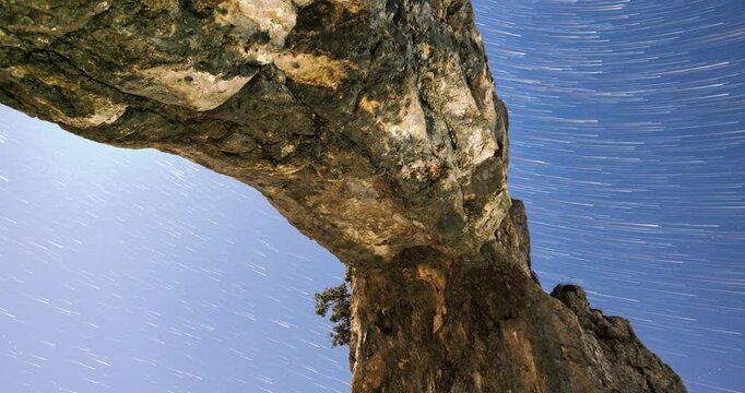 Timelapse of star trails over the Porta di Prada rock formation in Alpe Cainallo, showcasing the natural beauty of the night sky with vivid motion and a stunning landscape backdrop