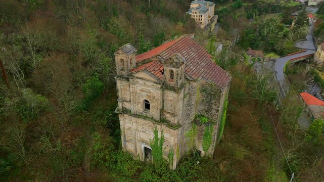 Abandoned church, Santa Maria di Lago Pigo, Nostra Signora di Nogareto or Madonna dell&rsquo;Assunta with gray stone, red tile roof, dense vegetation, and wooded hills. Aerial top-down orbit