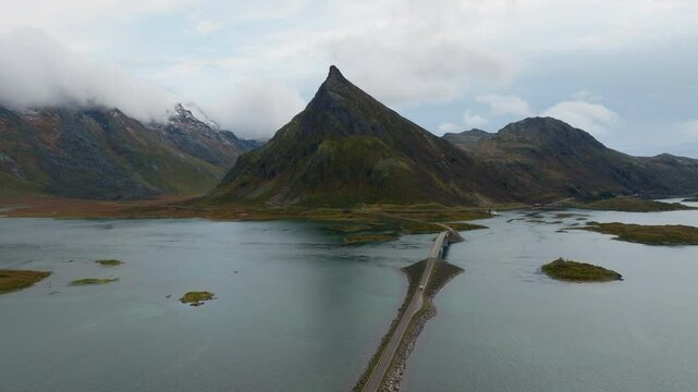 Aerial view of fredvang bridge surrounded by dramatic mountains under a cloudy sky, Lofoten, Norway