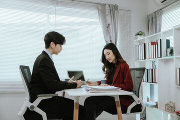 Team of corporate professionals working together in modern office to analyze financial charts and business reports. Businesswoman leading strategic discussion.