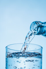 Crystal clear water being poured into a transparent glass, creating refreshing ripples and bubbles