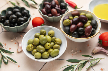 Bowls of green and black olives with tomatoes, garlic, olive oil, salt and pepper flakes