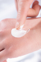 Cosmetic texture white creamy swatch on woman hand 