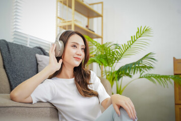A woman is sitting on a couch with her headphones on