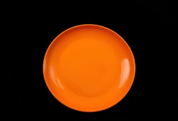 Vibrant orange plate against a stark black backdrop, dish, top view