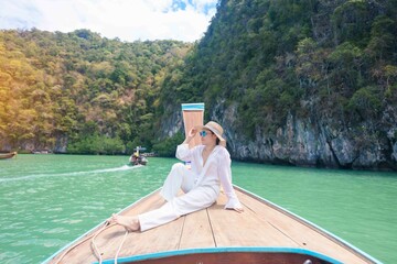 Happy Woman tourist in private longtail boat trip to koh Hong lagoon island at Krabi, Thailand....