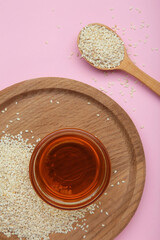 Sesame seeds and sesame oil on pink background