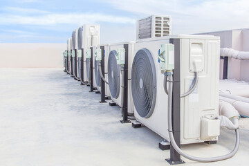Air conditioning (HVAC) on the roof of an industrial building with blue sky and clouds.	