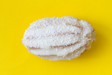 Eclair with white glaze on a yellow background. One eclair close-up.