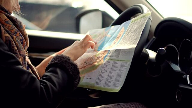 Traveler reading an open map while seated inside car