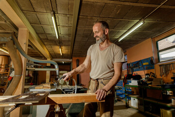 Carpenter Cleaning Table Saw and Workspace with Compressed Air in a Workshop.