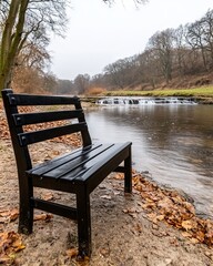 Fototapeta premium Black park bench by a river on an autumn day