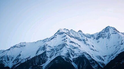 Obraz premium Capture the serene and majestic beauty of a snow-capped mountain landscape, with towering peaks glistening under a soft winter sun.