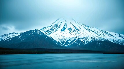 Capture the serene and majestic beauty of a snow-capped mountain landscape, with towering peaks glistening under a soft winter sun.